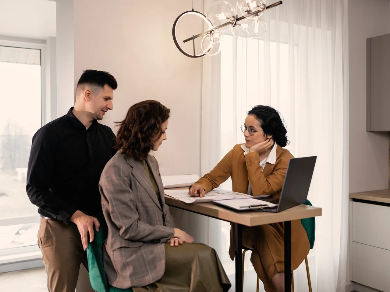 A wedding planner reviews plans with a couple at a table